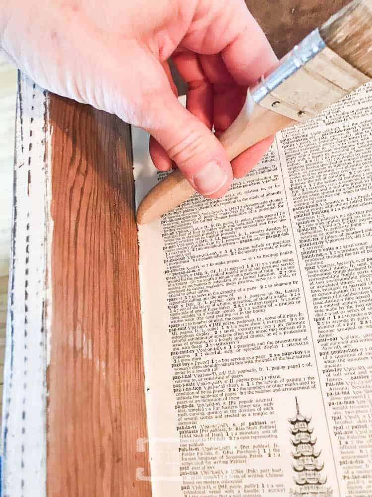 Lady using a paint brush in a DIY drawer liner tutorial.