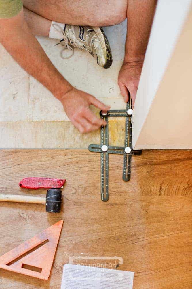 man using an angle tool to measure and cut new flooring in small bathroom makeover project