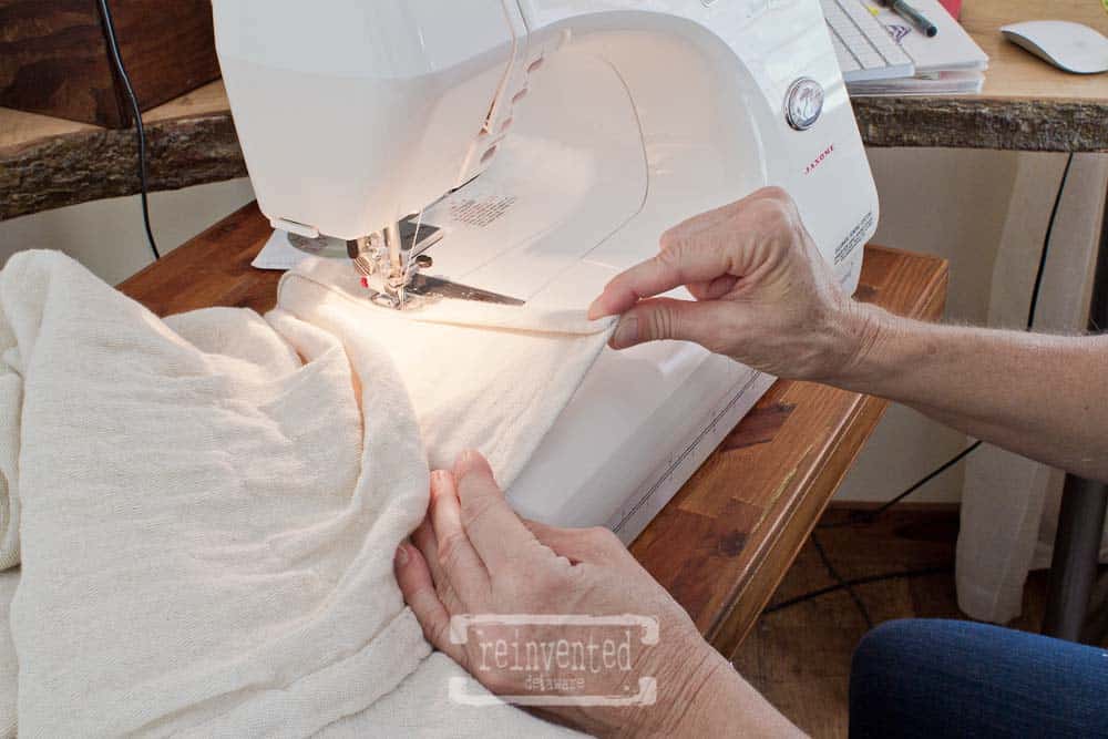 lady stitching the last seam on a farmhouse-style drop cloth shower curtain