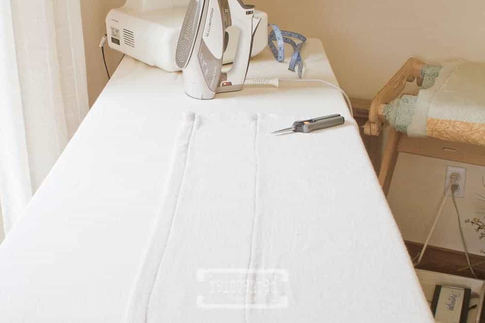 hemmed drop cloth, scissors, iron and serger sitting on top of ironing board