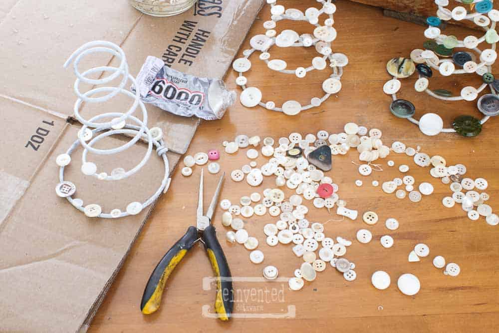 Used box springs, vintage buttons, pliers and E6000 glue laying on a table.