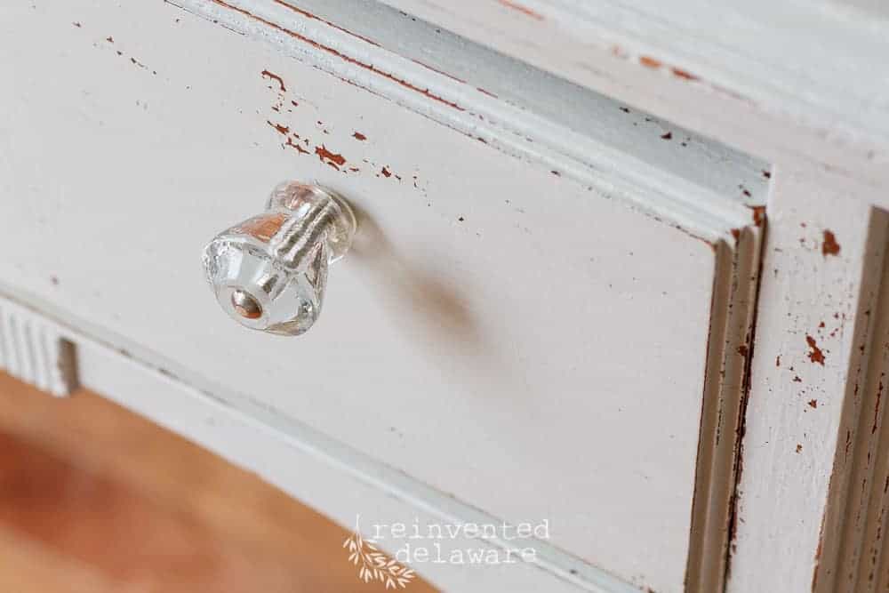 Close up of a glass drawer pull on a vintage cabinet.
