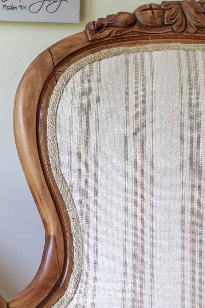 close up of carved wood on Victorian chair that has bee reupholstered with grainsack style fabric