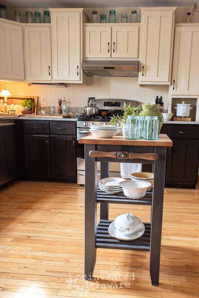 Staged small kitchen island that was thrifted and repurposed from a kitchen storage cart. Vintage mason jars and ironstone sitting on the shelves.