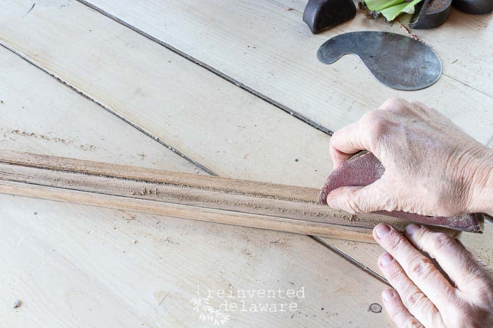 lady using sandpaper on a fold down secretary desk