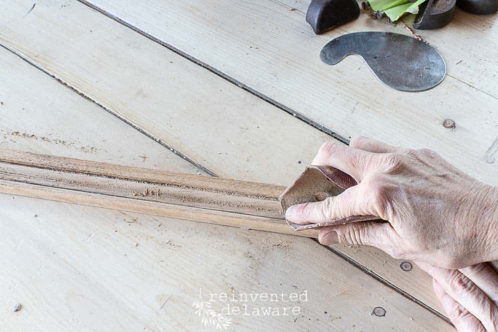 lady using sandpaper on afold down secretary desk