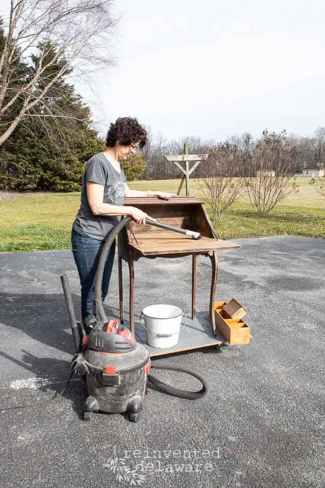 lady vacuuming the sanding dust from an antique fold down secretary desk