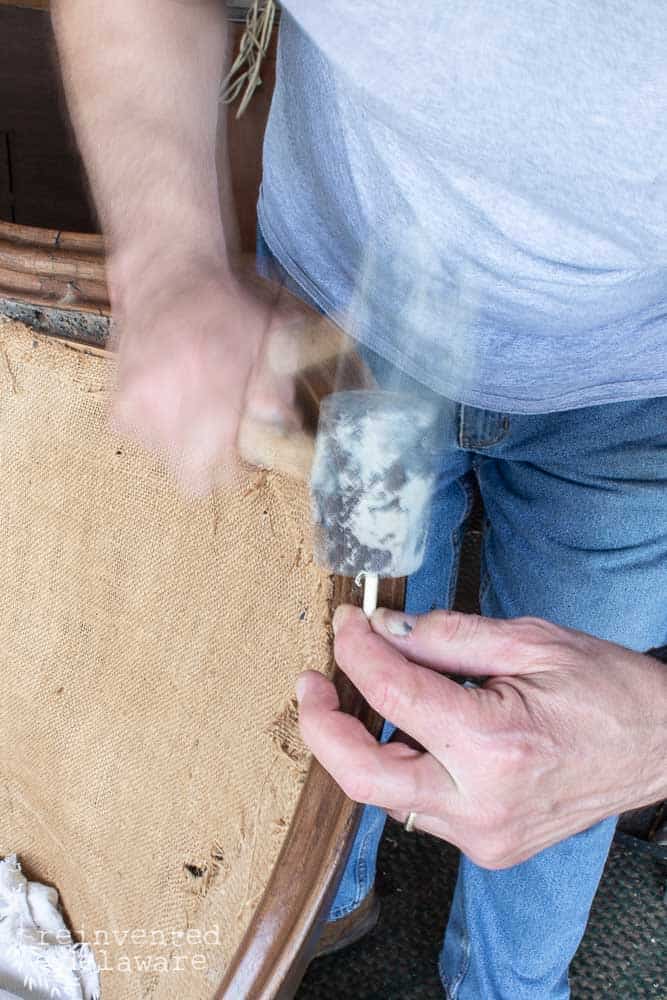 Man using a mallet for a repair on an antique sofa.