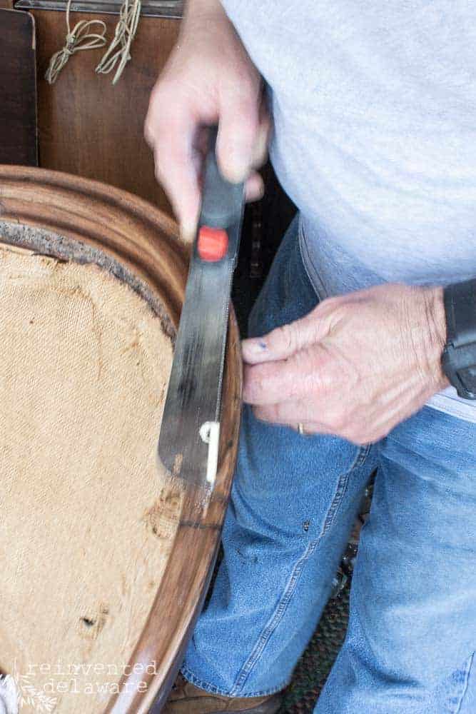 Man using a pull saw to make a repair on an antique sofa.