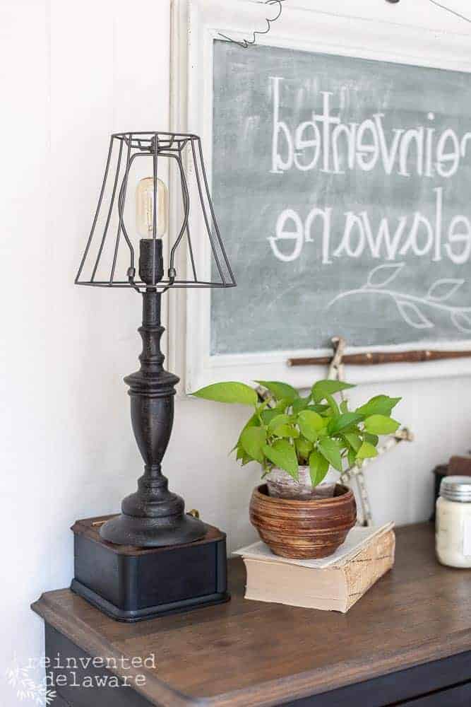 side view of lamp that had a makeover with milk paint and is staged on top of vintage dresser with a plant and wall decor