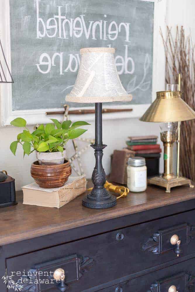 lamp makeover staged on top of antique dresser with various items like a plant