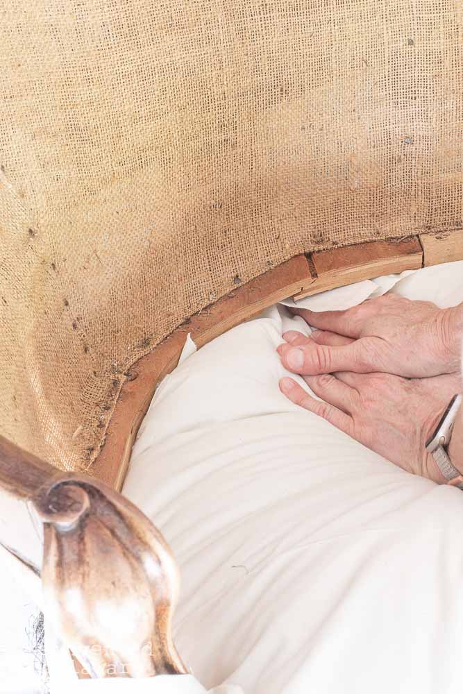 Lady showing how to push upholstery fabric towards the back of an upholstered piece of furniture.