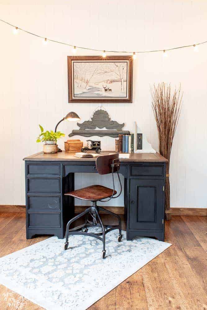 Front view of antique desk that has been madeover using black milk paint. Various items on the desktop.