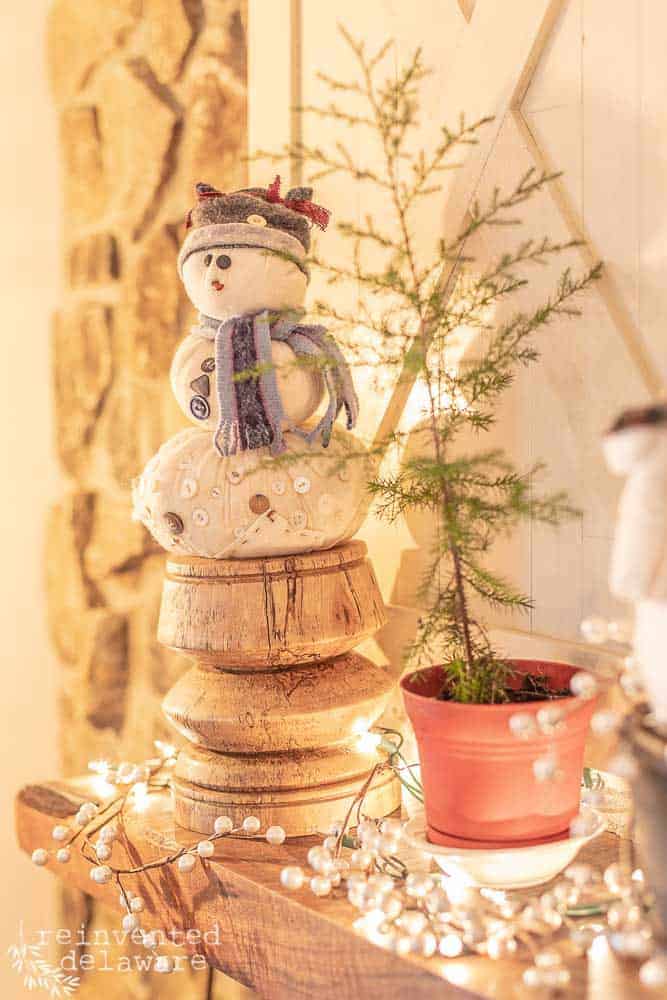 handmade snowman on mantle with spruce sapling in potted container
