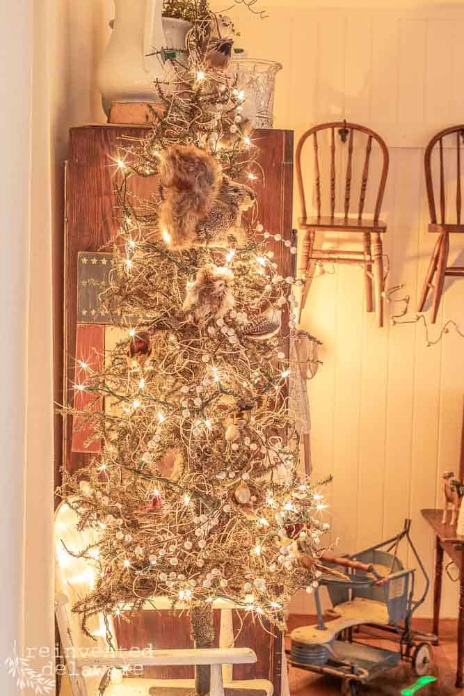 Christmas tree with woodland creature ornaments. tree is on a vintage highchair