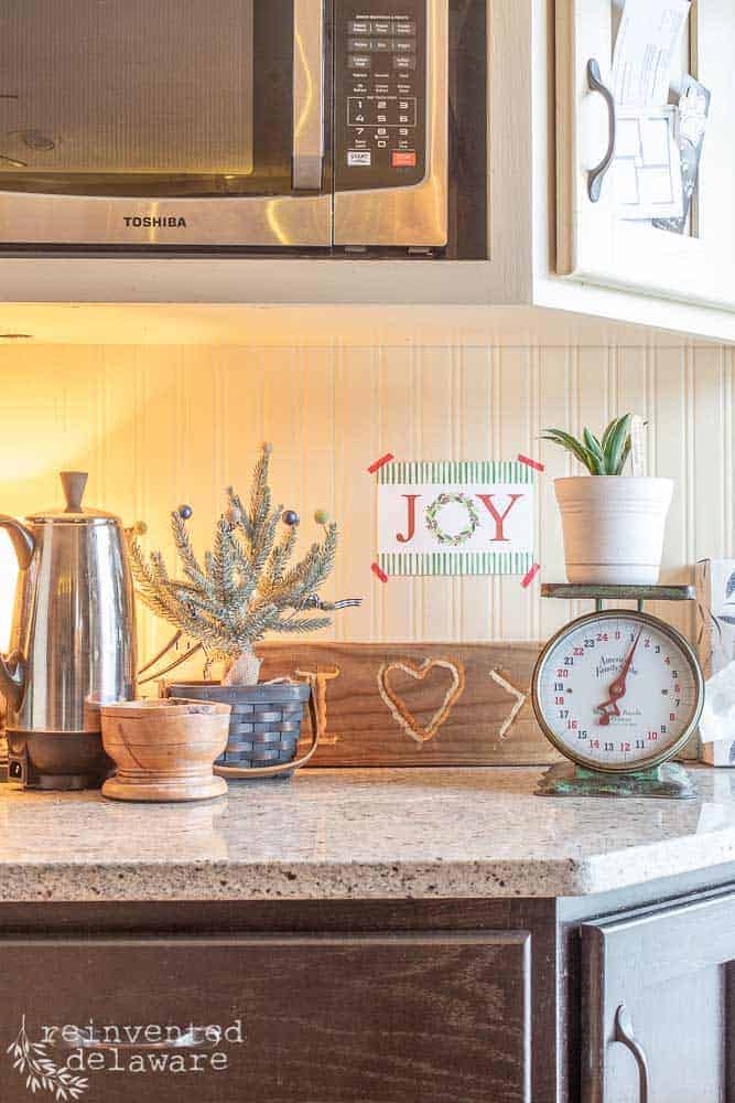 cage area on kitchen counter showing percalator, small Chrismas tree and "Joy" wall art