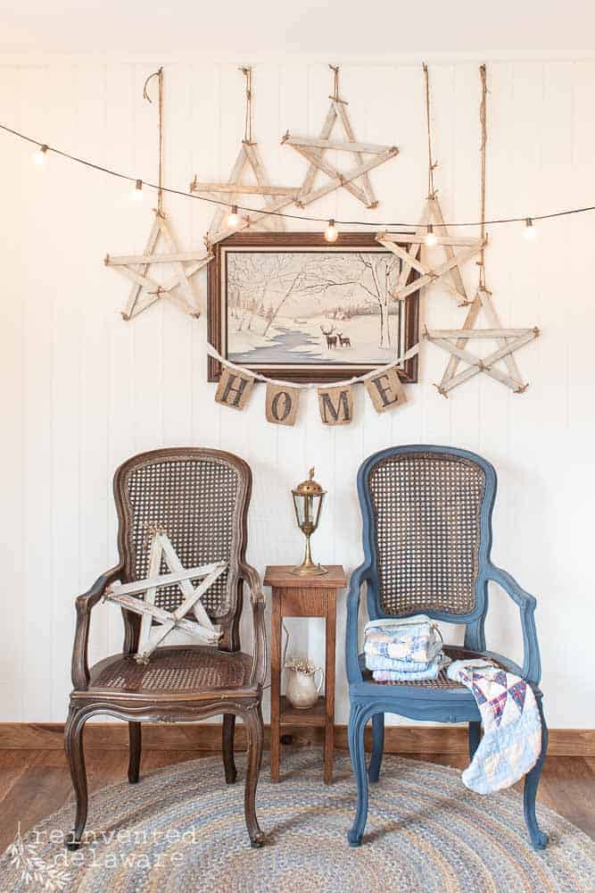 two wicker chairs, one painting, 'home' wall banner and five hanging handmade stars vignette