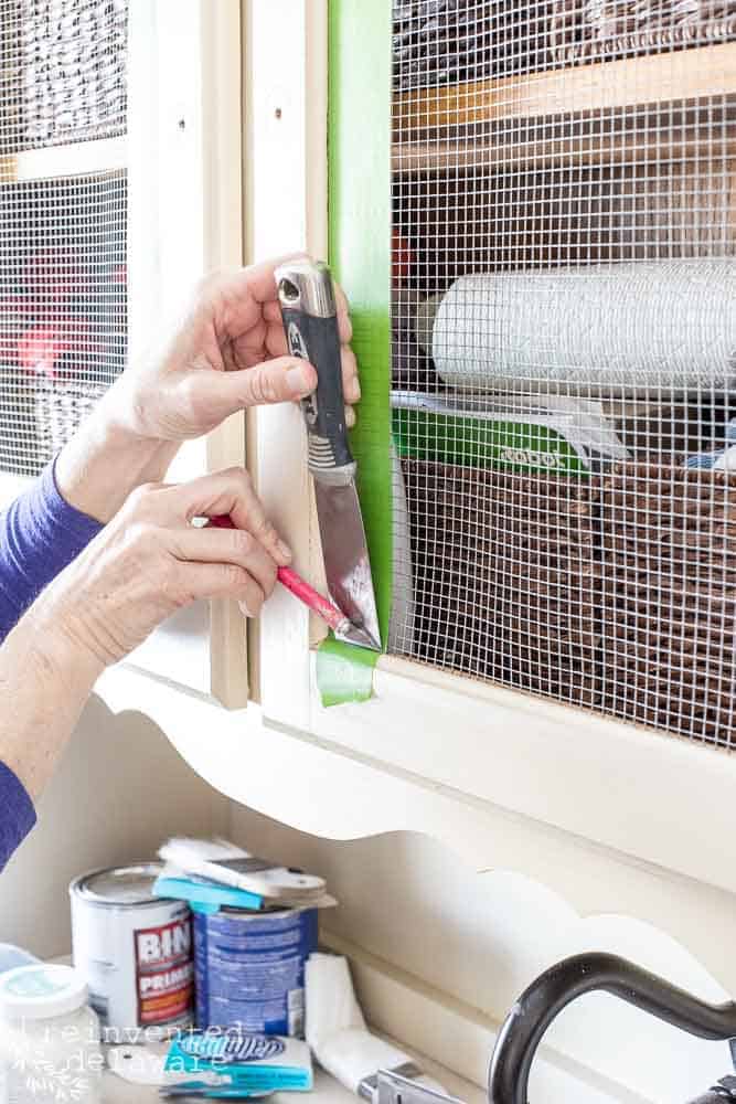 close up of lady using frog tape to prep cabinet for painting