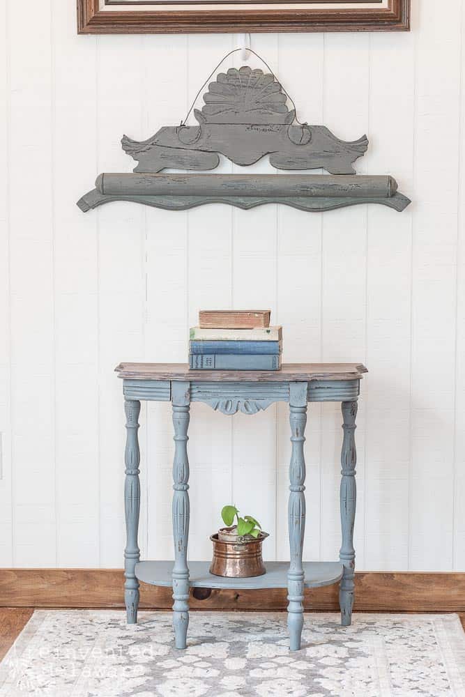 Demilune table with stack of books on top and wall decor