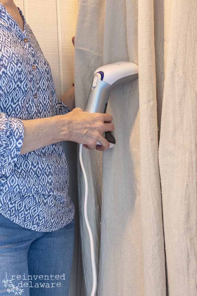 lady using steamer on dropcloth curtain/close up shot