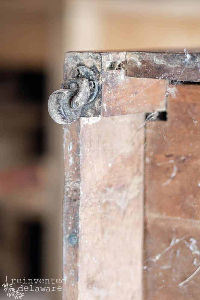 close up of wooden caster on antique washstand before the easy makeover