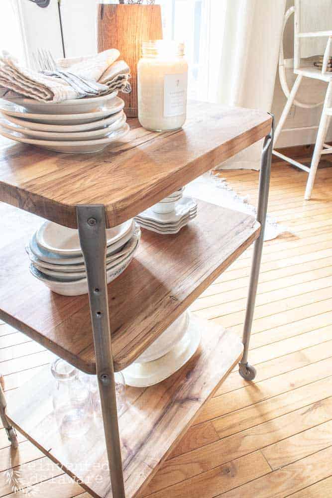 side view of upcycled school cart showing reclaimed lumber shelves styled with dishes and candle