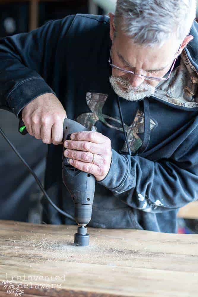 man using power drill to drill larger opening for vessel sink in the repurposed dresser into a bathroom vanity blog post