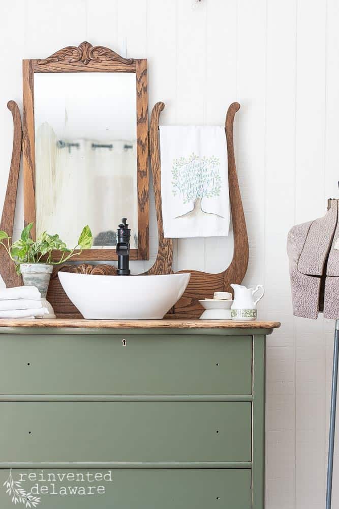 3/4 shot of dresser after a makeover with an added vessel sink and faucet staged with various bathroom items