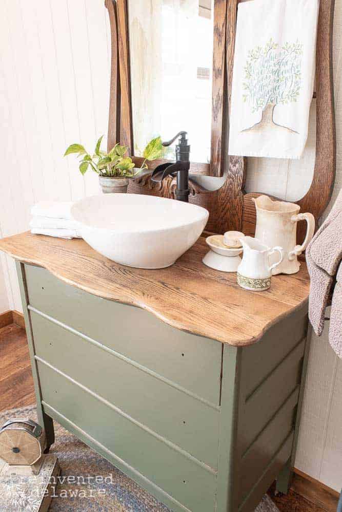 wide shot of top of dresser showing restored wood top staged with various bathroom vanity items