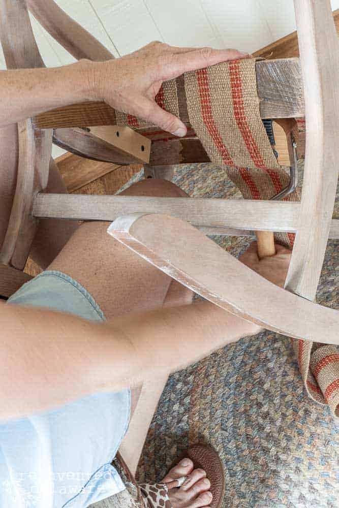 lady using upholstery webbing stretching on rocking chair upholstery project