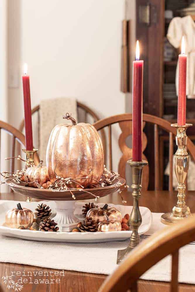 copper leaf pumpkins sitting on dining table as a center piece with vintage brass candlesticks