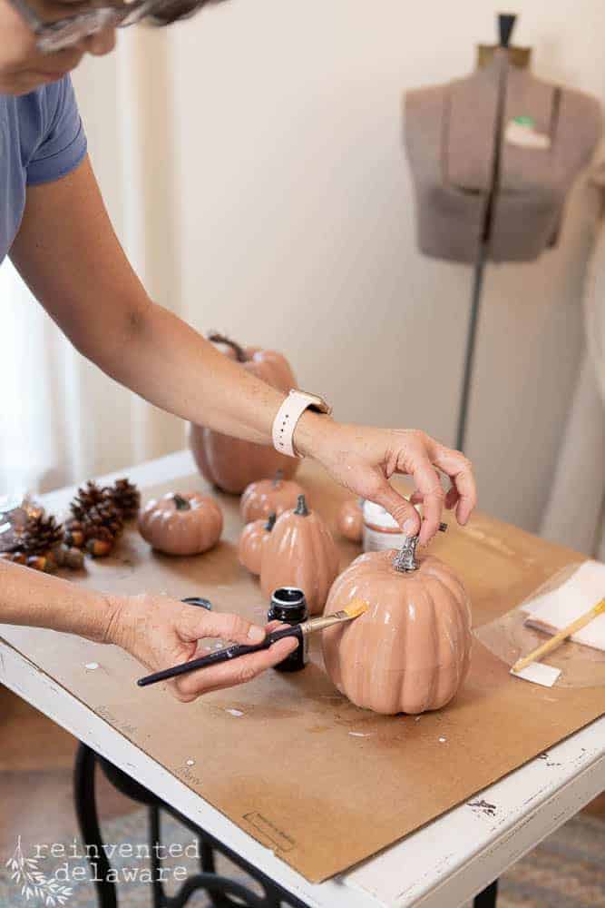 lady applying metal adhesive to craft store pumpkin for learn how to copper leaf a pumpkin blog post