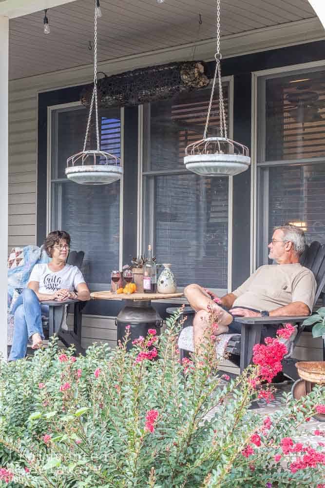 two people sitting on Adirondack chairs on a front porch