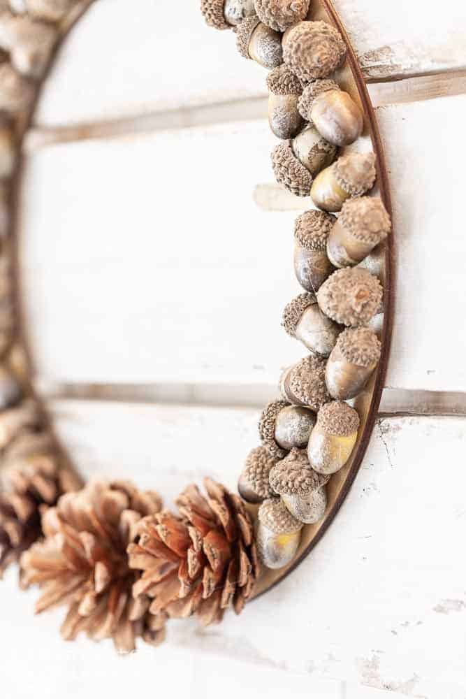 Side view of DIY fall wreath with acorns and pine ones glued to a wood wreath frame.
