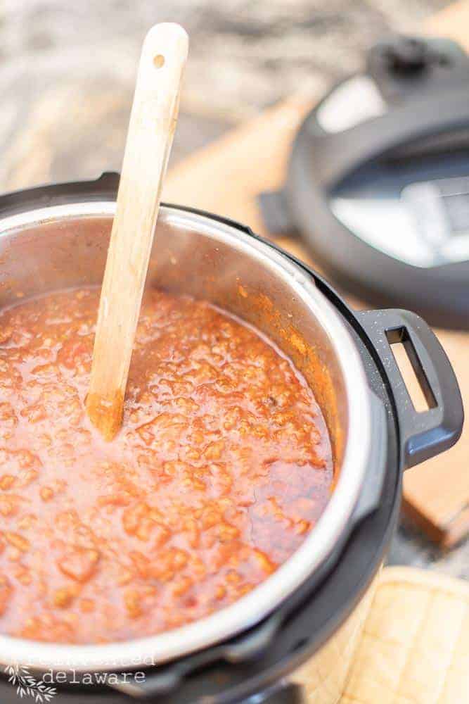 Instant Pot spagehetti sauce still in the Instant Pot with wooden spoon for stirring