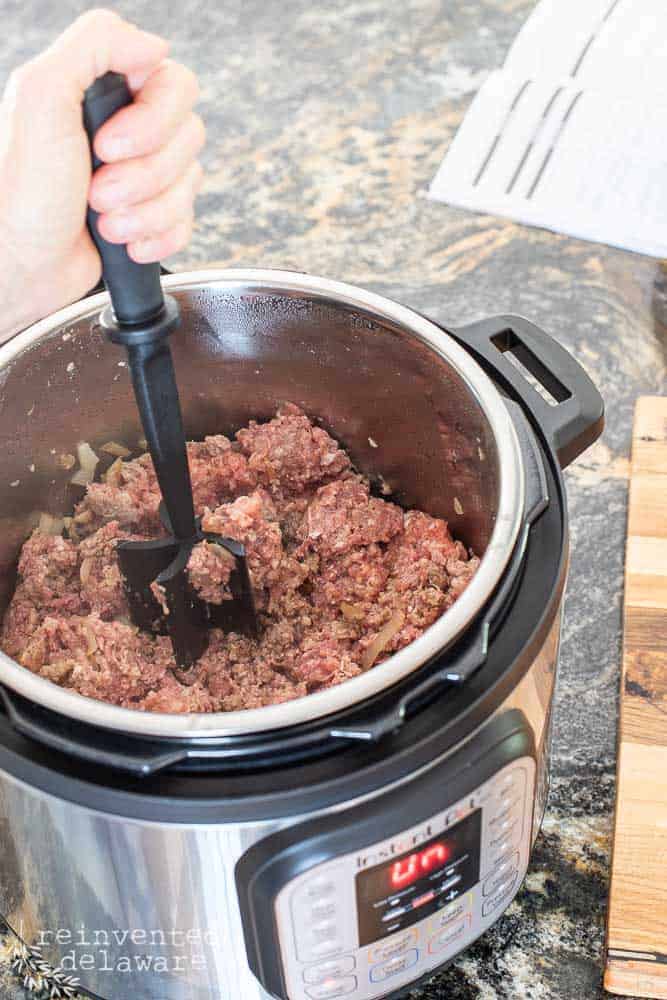 lady chopping up the meat in the Instant Pot for the spaghetti sauce recipe