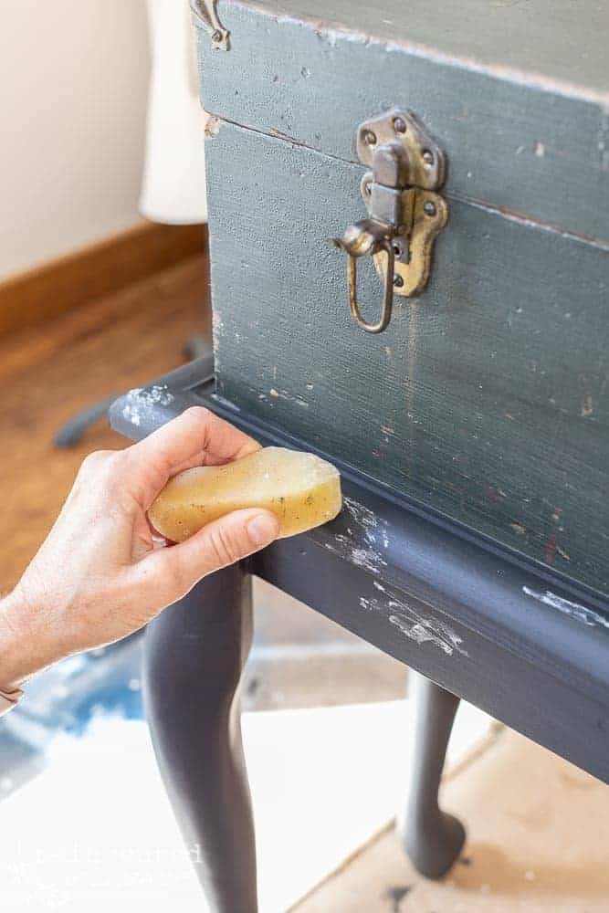 lady using a wax puck on an upcycled wooden tool chest to act as a resist to paint