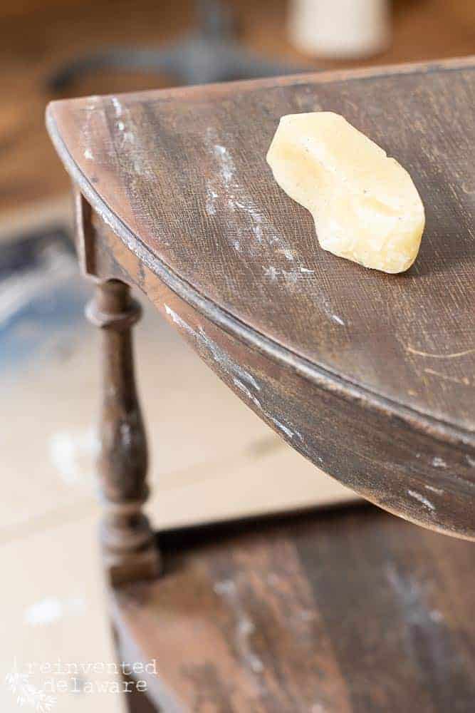 close up of beeswax puck sitting on top of a small table. beeswax has been rubbed onto the table to create a resist for the chalk mineral paint