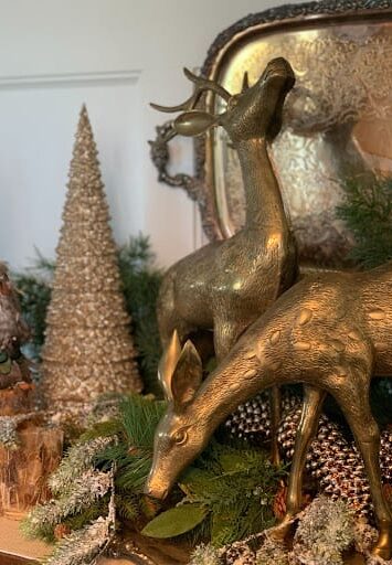 Christmas decor displayed with brass deer, silver platter and gold Christmas tree