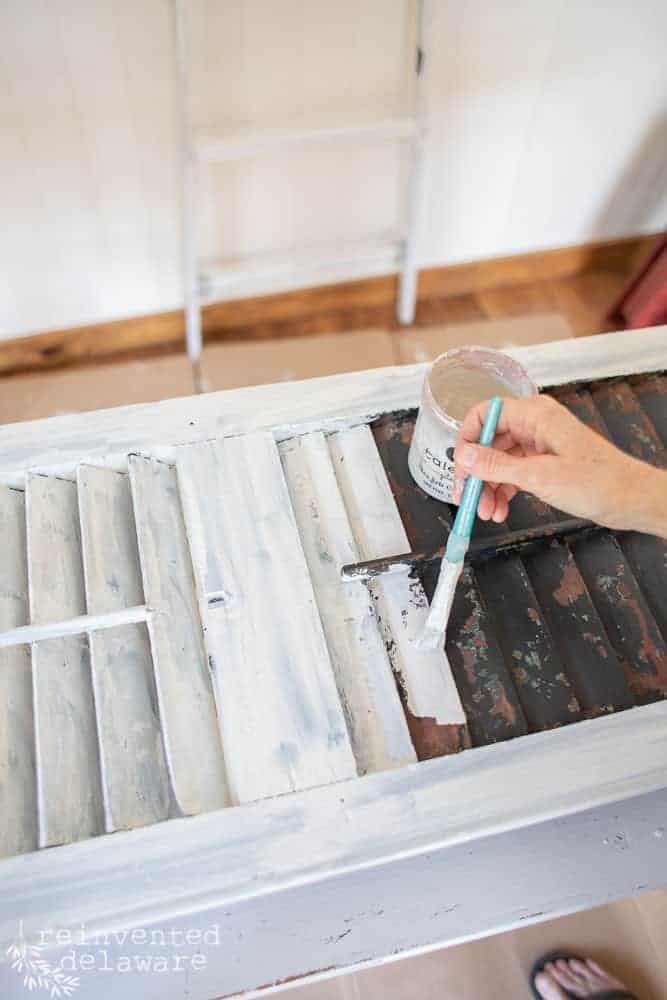 lady painting old shutter with Miss Mustard Seed Milk Paint in Shutter Gray