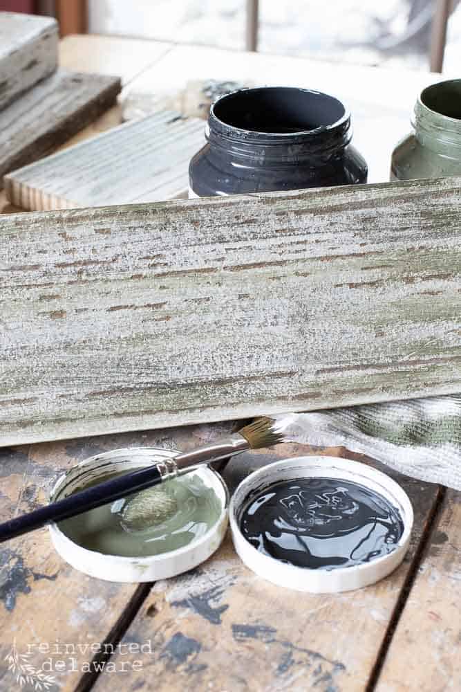 reclaimed fence boards being painted with mixture of green paint and black paint to create a Christmas tree color