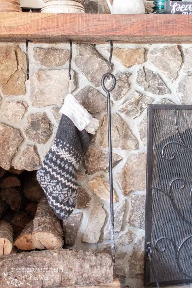 handmade sweater stocking hanging from a fireplace mantle that also shows a stone fireplace
