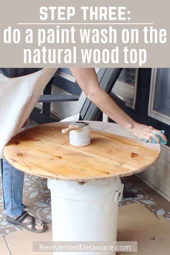 Graphic with text overlay " Step Three: do a paint wash on the natural wood top" with lady showing how to do the paint wash technque.