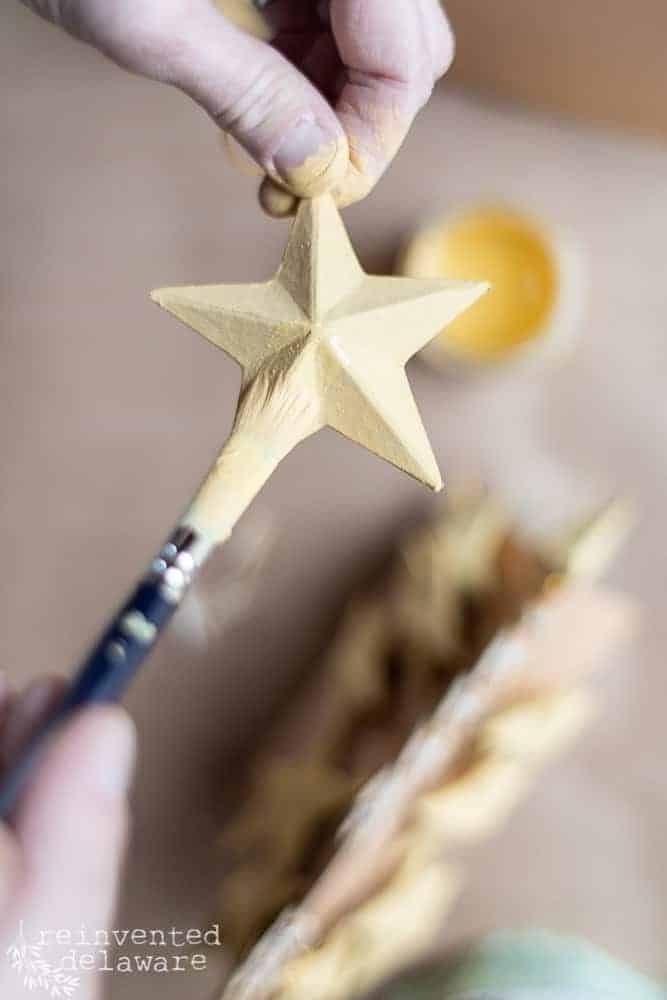 Lady painting a paper mache star to use as a decoration for the Christmas tree.