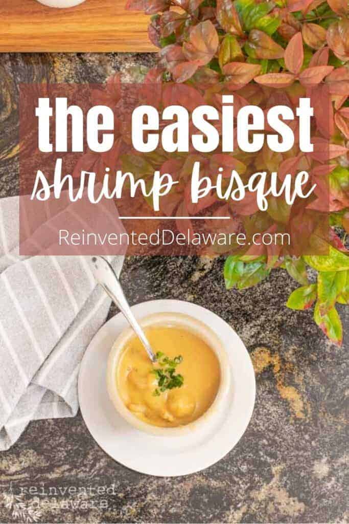 Pinterest graphic with text overlay "the easiest shrimp bisque Reinvented Delaware.com" and a cup of the soup at the bottom of the graphic.