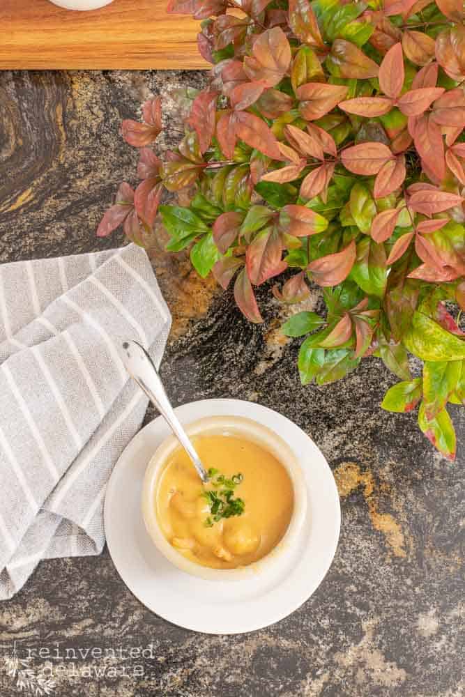 Finished cup of shrimp bisque made in the Instant Pot staged with a display of Nandina and a gray napkin.