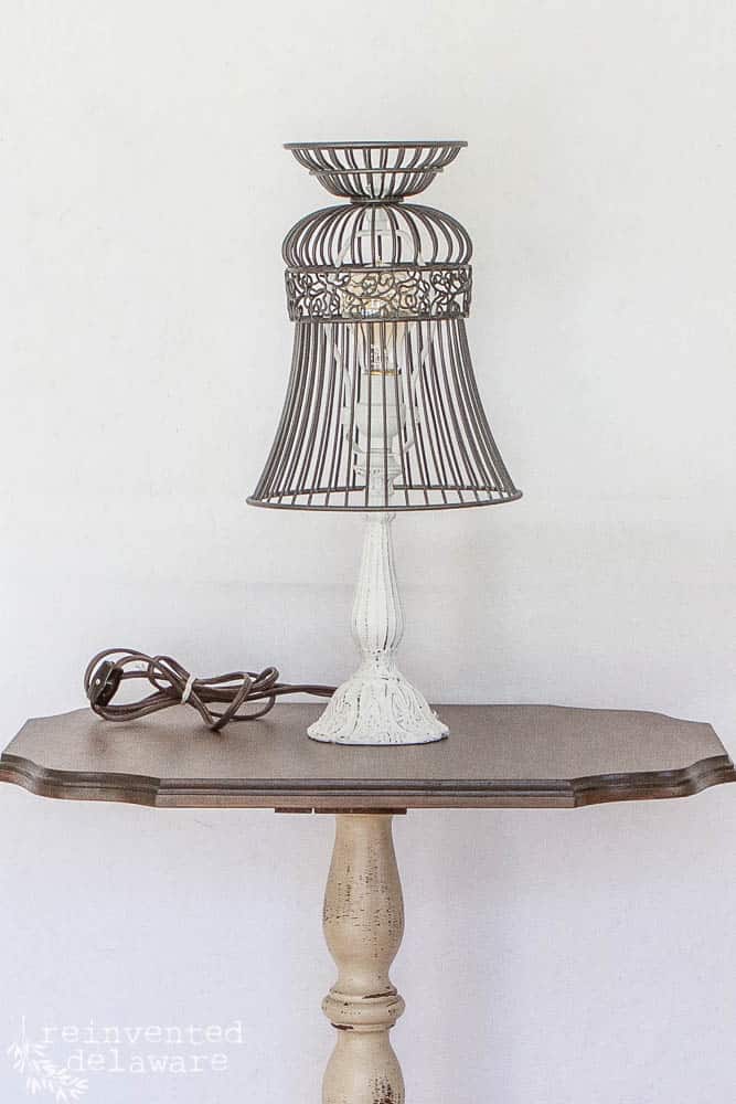 Vintage lamp that has been painted in white chalk paint and has a shade upcycled from a modern day wire basket to show how to upcycle and repurpose thrift store items into farmhouse style home decor.