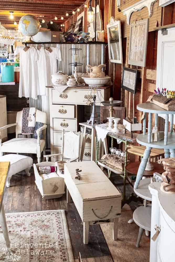 Inside of a vendor booth in an antique and vintage store called Wilderlove Handmade and Vintage in Greenwood Delaware. The booth is called Reinvented Delaware and many upcycled and repurposed items are on display including vintage painted furniture and farmhouse style home decor.