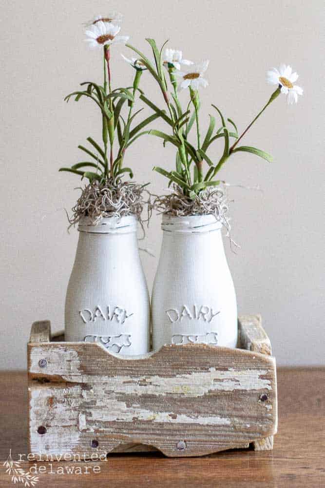 Picket fence sections upcycled into a small caddy to hold flowers in painted milk bottles.