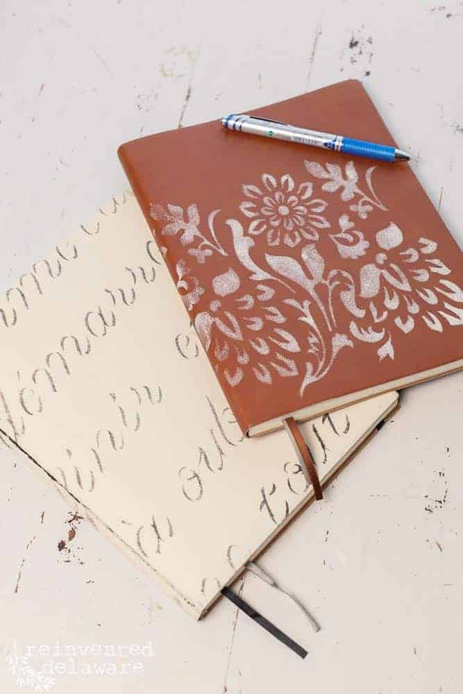 Two journals laying on a desk that have been stenciled with a floral stencil from Belles and Whistles from Dixie Belle and paint.